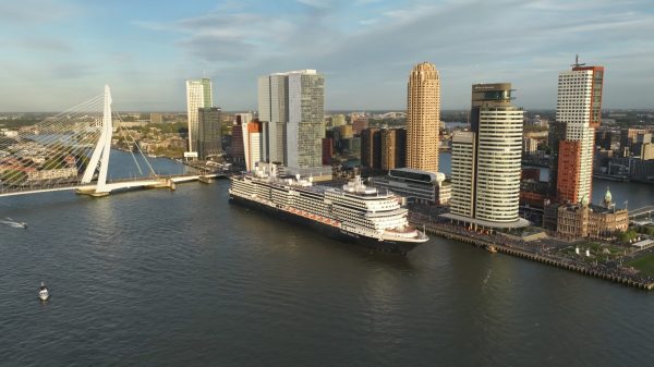Holland America Line's Rotterdam VII departed the city of Rotterdam, the Netherlands, today on its historic 150th Anniversary Transatlantic Crossing. The 15-day journey recreates Holland America Line's maiden voyage of Rotterdam I that departed the city 150 years ago today. The crossing follows the path of that first sailing to New York, with calls at Le Havre, France, and Plymouth, England. The brick building with towers in the lower right is the former headquarters for Holland America Line and is now Hotel New York.